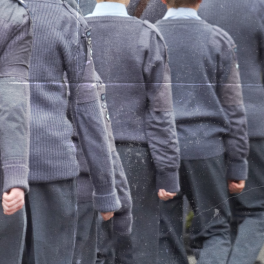 student cadets in grey uniforms marching away from the camera