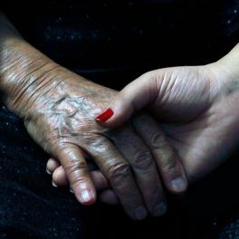 two hands holding, one from an older woman one from a younger woman