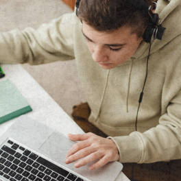 Teen Boy typing on laptop and referencing a book