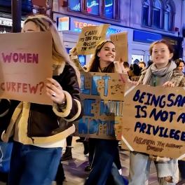 a group of people walking down the street holding cardboard signs