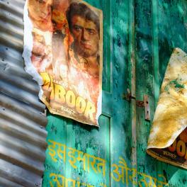 distressed Bollywood movie posters on a painted wall