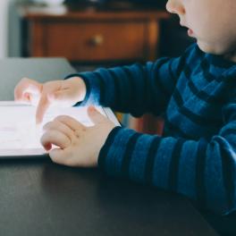 child sitting at a kitchen table using an ipad