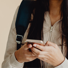 a young woman wearing a beige jacket holding her phone