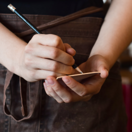 a young person writing down an order on a notepad while wearing an apron