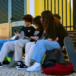 Four young people on a bench with skateboards