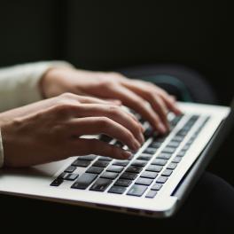 A cropped image of someone typing on a computer.