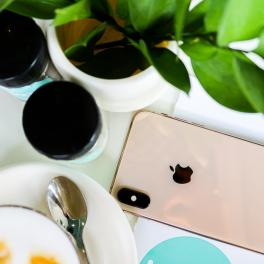 An over view of an Iphone on a table next to some supplement bottles and a coffee. 