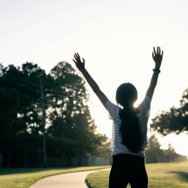 A silhouette of a young girl with her arms in the air.