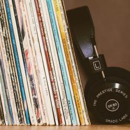 A stack of records next to a set of headphones.