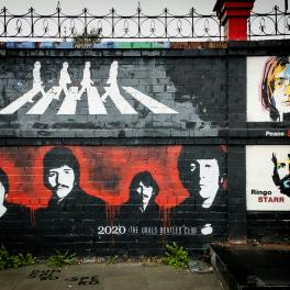 A photograph of a Beatles mural. The top half shows the Beatles on Abbey Road and the bottom half displays their faces.