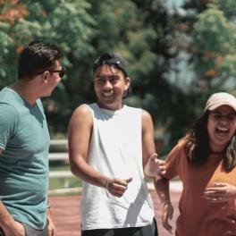 Three young adults laughing together.