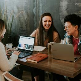 Three young people networking at a table together.