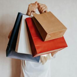 Shopping bags held up in front of a person.
