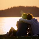 two young people hugging and looking out over the sunset