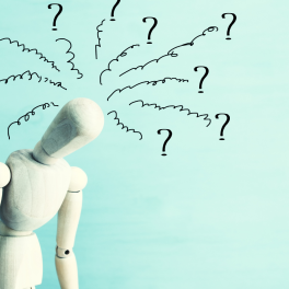 A wooden mannequin with question marks drawn around its head