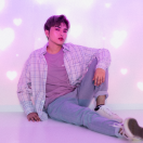 A photo of a k-pop inspired man sitting up against a wall