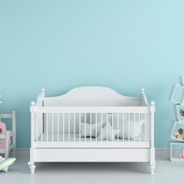 an image of an empty crib against a blue wall surrounded by toys