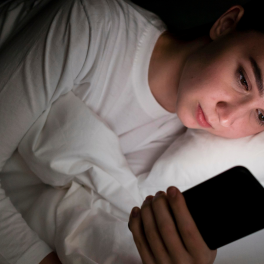 Young woman in bed staring at her phone