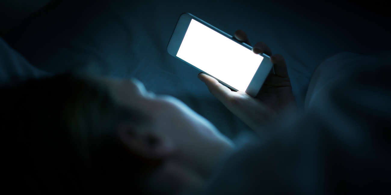 someone lying in bed looking at their phone screen