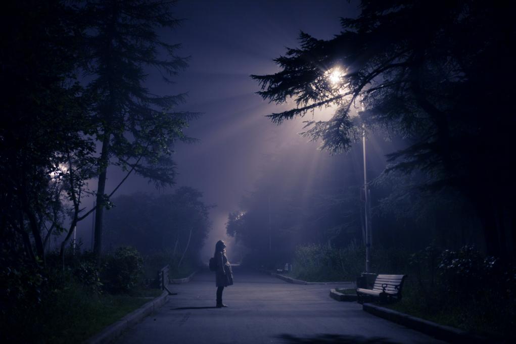 young woman standing under a light post at night