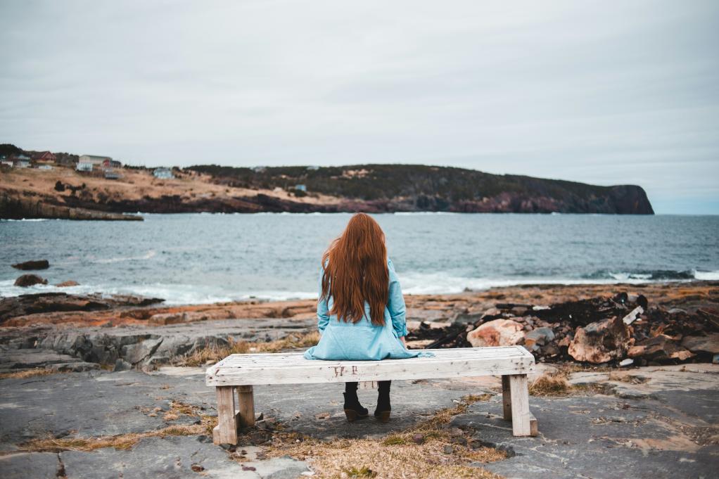 woman sitting on a bench facing the water