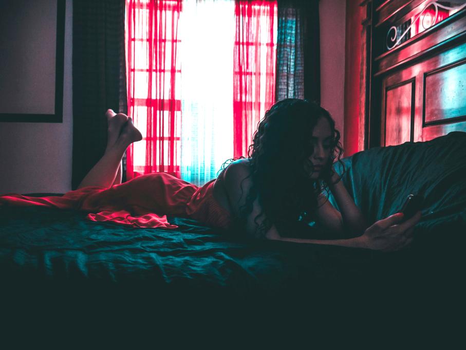 woman lying on a bed looking at her phone