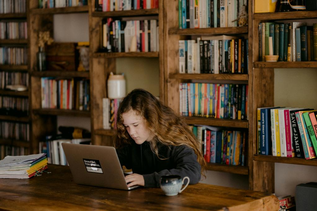 young girl typing on a laptop