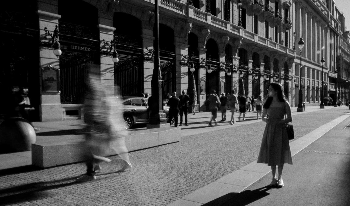 black and white photo pf a young woman walking down a city street 