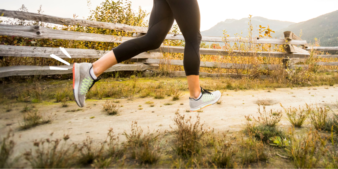 legs in black leggings and sneakers running on a path