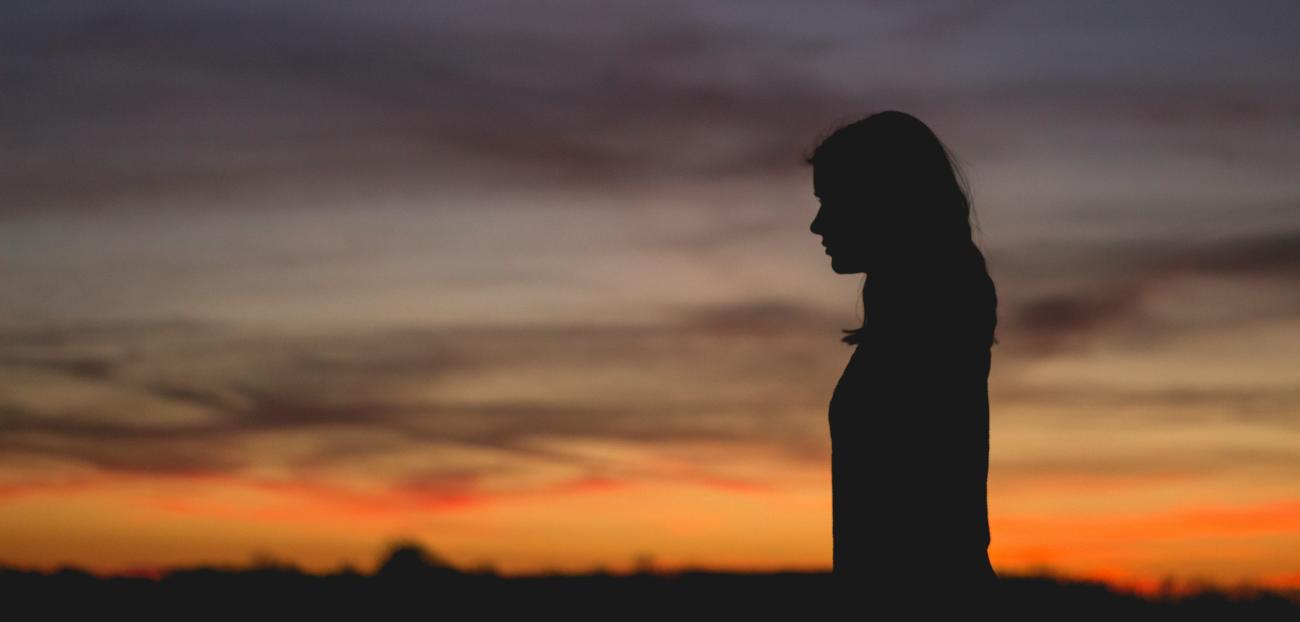 silhouette of a young woman in front of a sunset