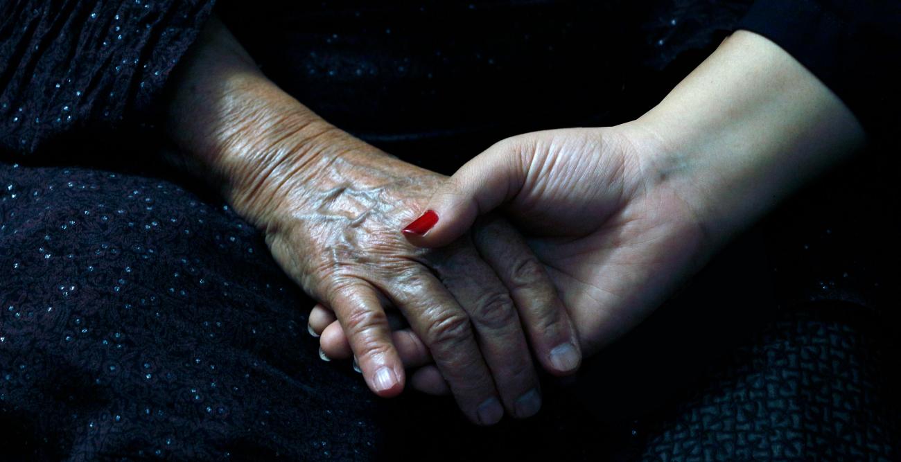 two hands holding, one from an older woman one from a younger woman