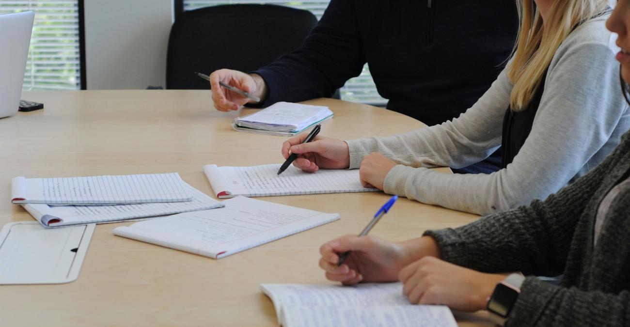a few people sitting at a table taking notes