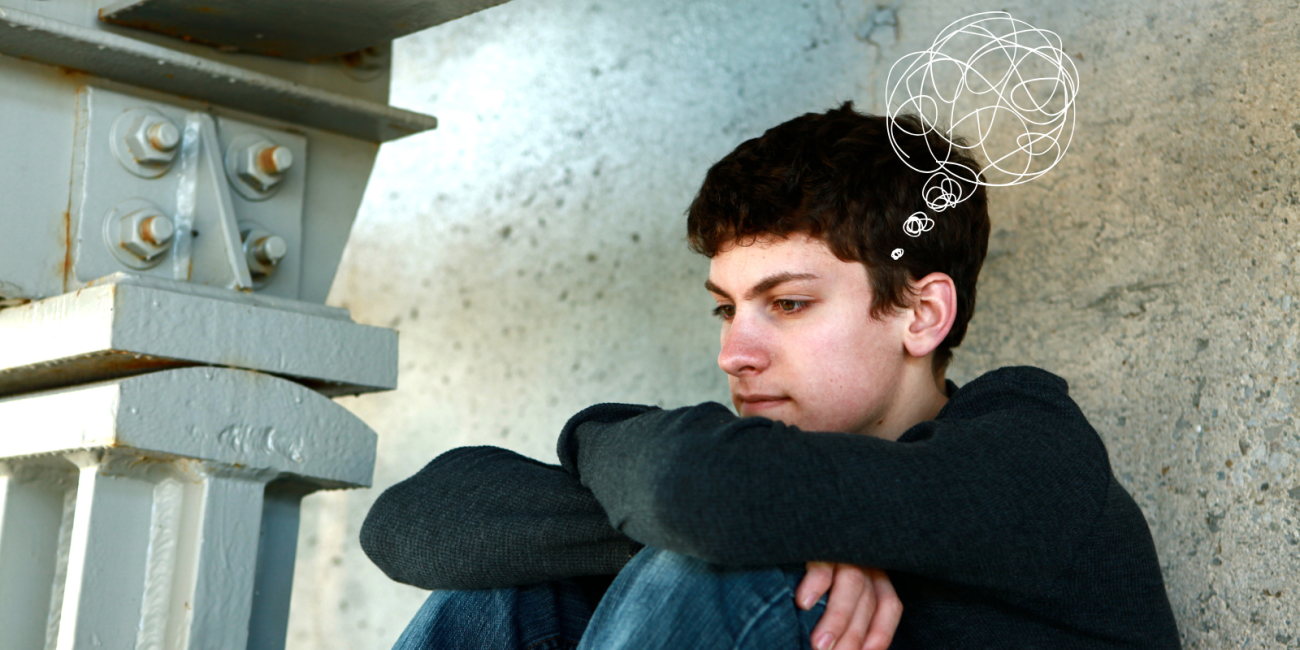 a young man sitting and thinking with a graphic of a scribbled thought bubble above his head
