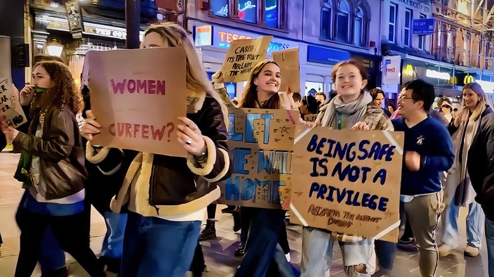 a group of people walking down the street holding cardboard signs