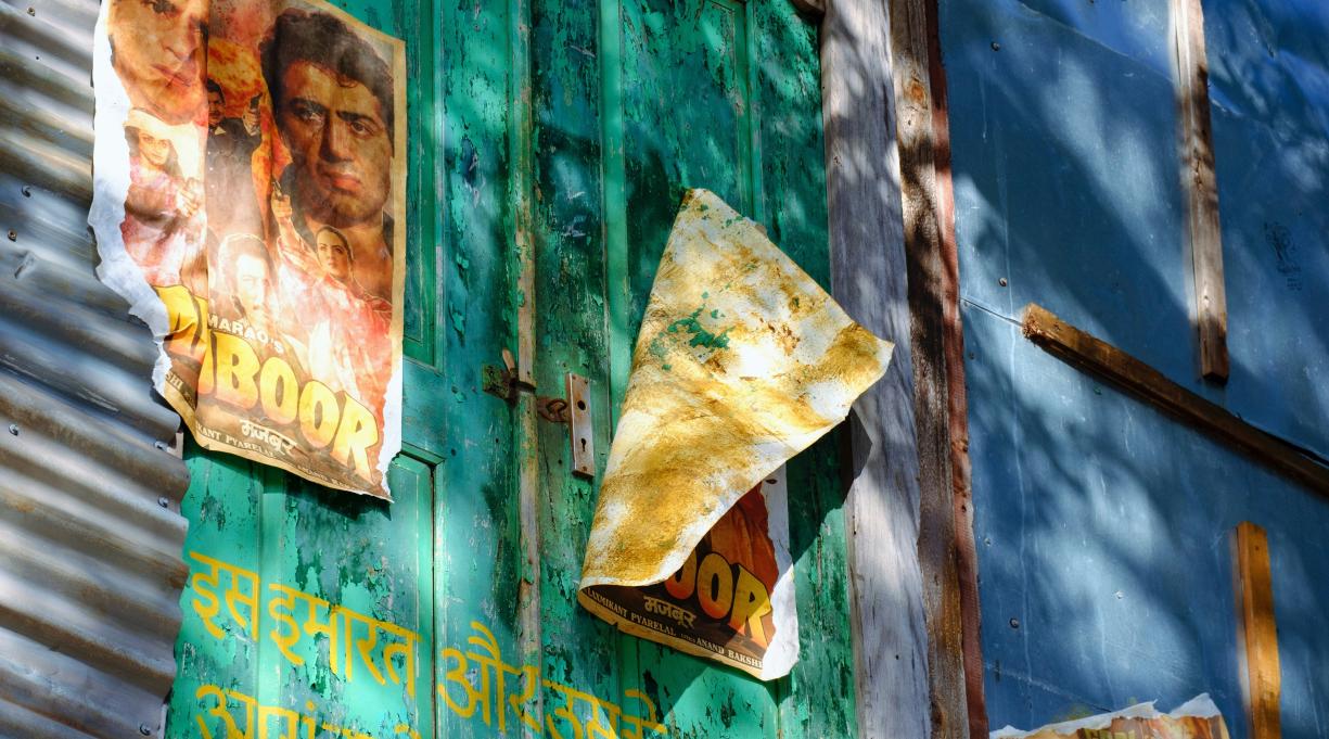 distressed Bollywood movie posters on a painted wall