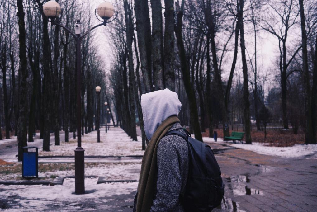 young man walking through a park with his hood up