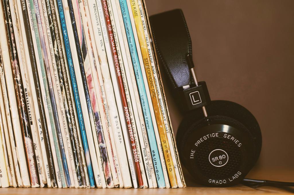 A stack of records next to a set of headphones.