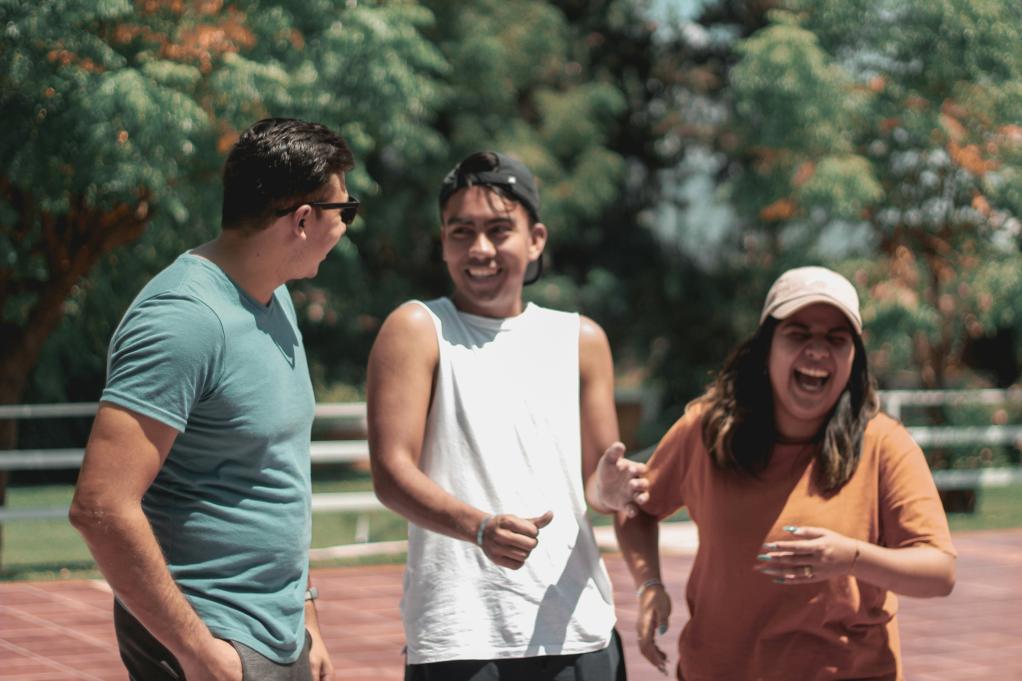 Three young adults laughing together.