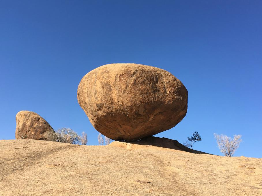 A desert rock with a blue sky behind it. 