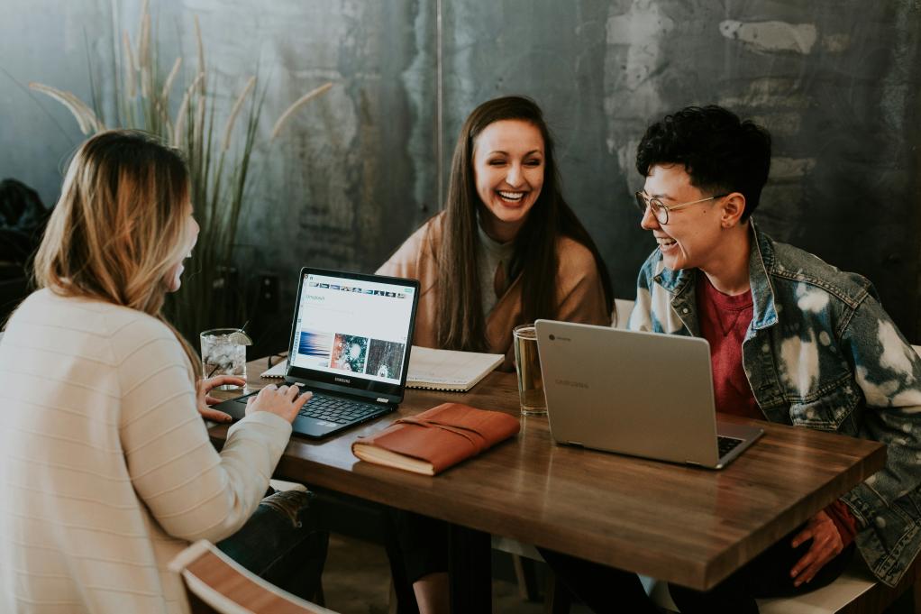 Three young people networking at a table together.