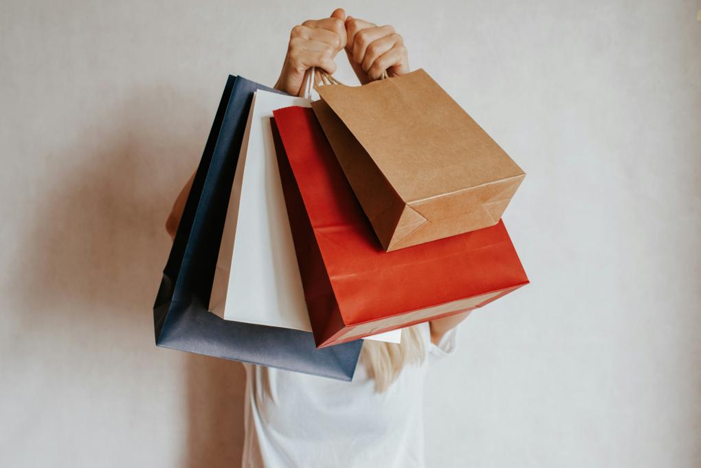 Shopping bags held up in front of a person.