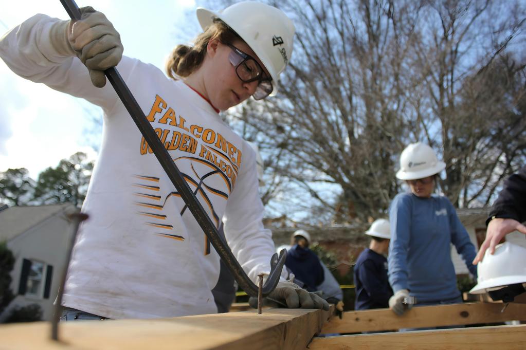 A young woman using a crowbar for woodworking.