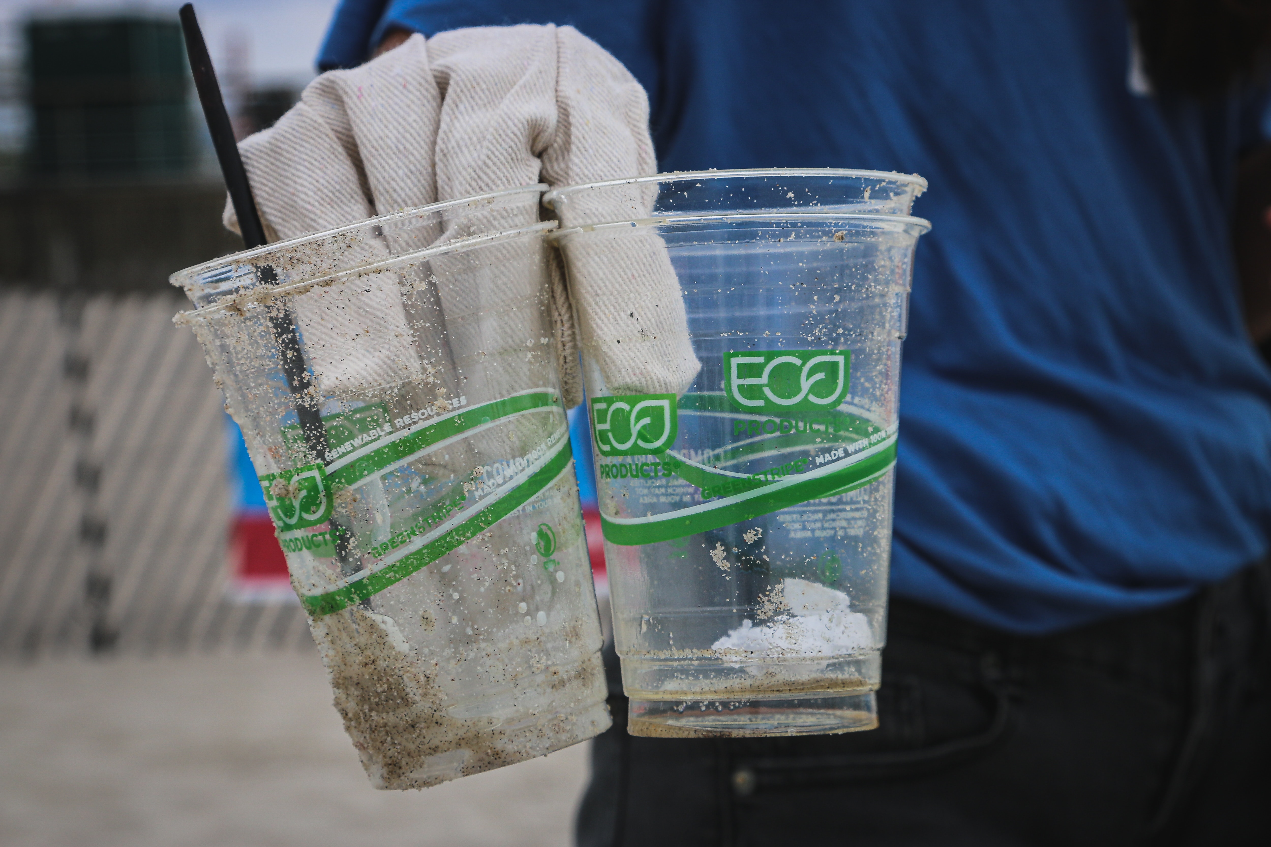 person holding plastic cups that were littered that have 'eco' written on them