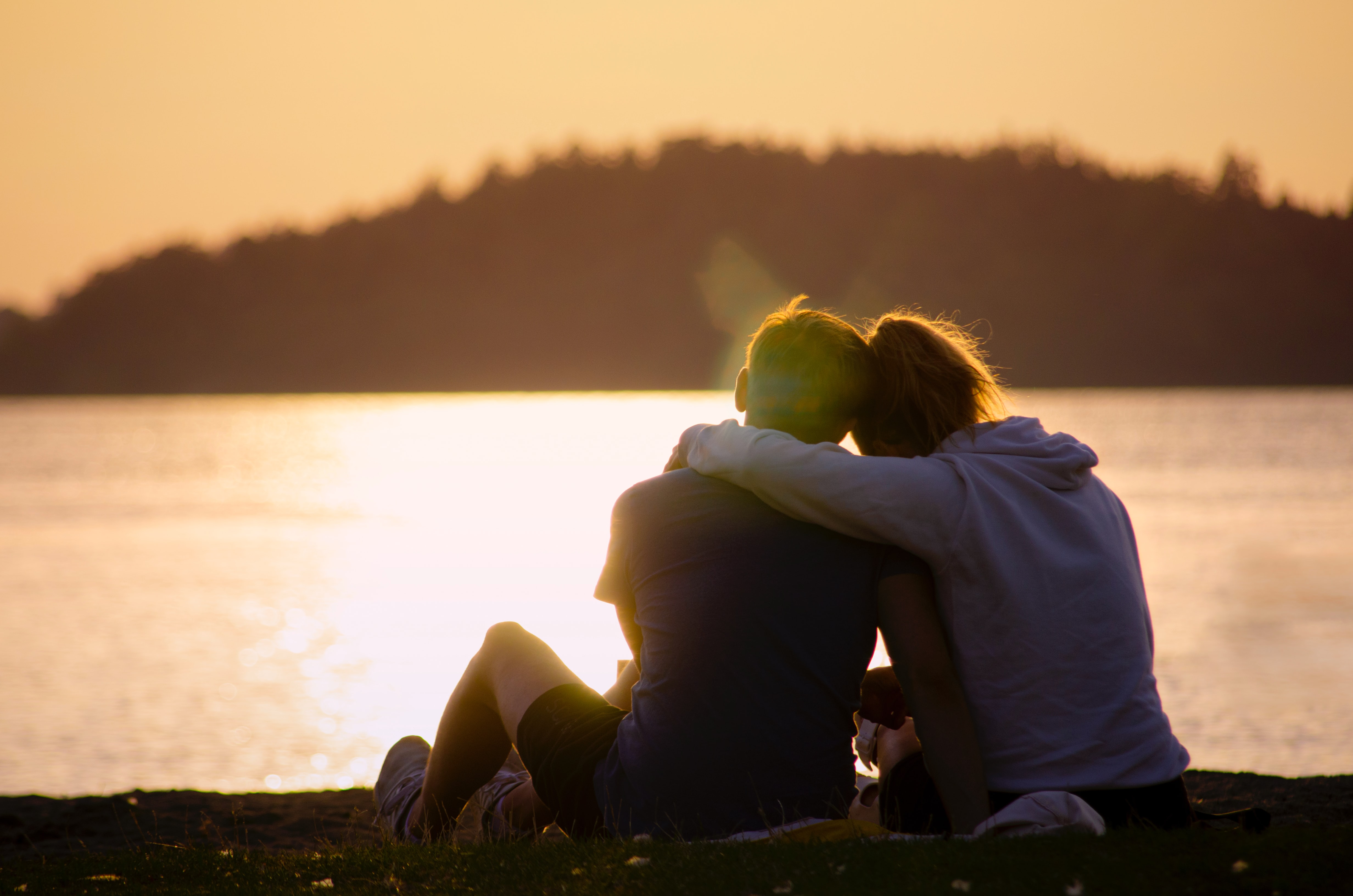 two young people hugging and looking out over the sunset