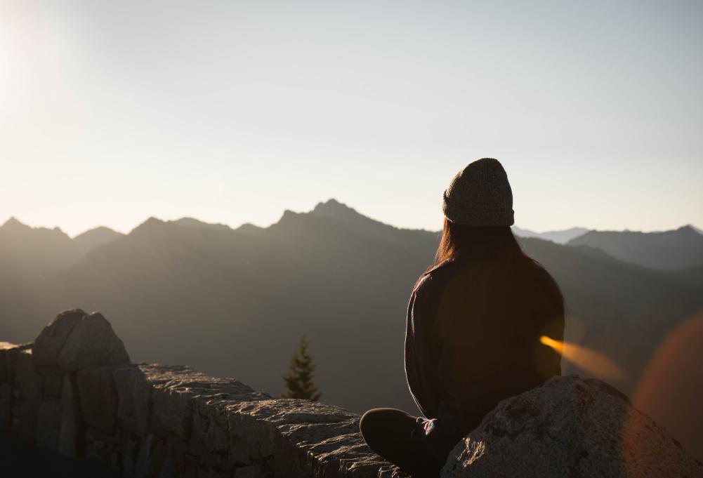 person sitting on a mountain meditating