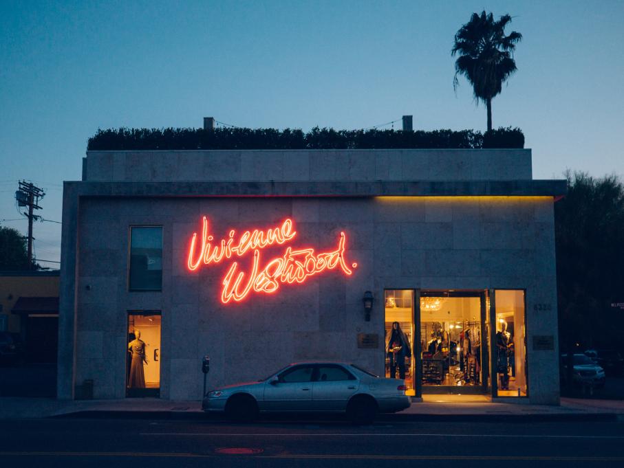 the outside of a shop with a neon sign that reads "vivienne westwood"