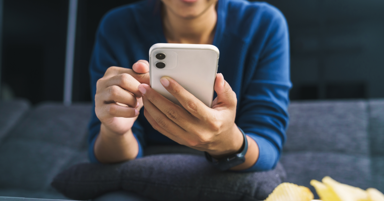 person in a blue shirt scrolling on their phone