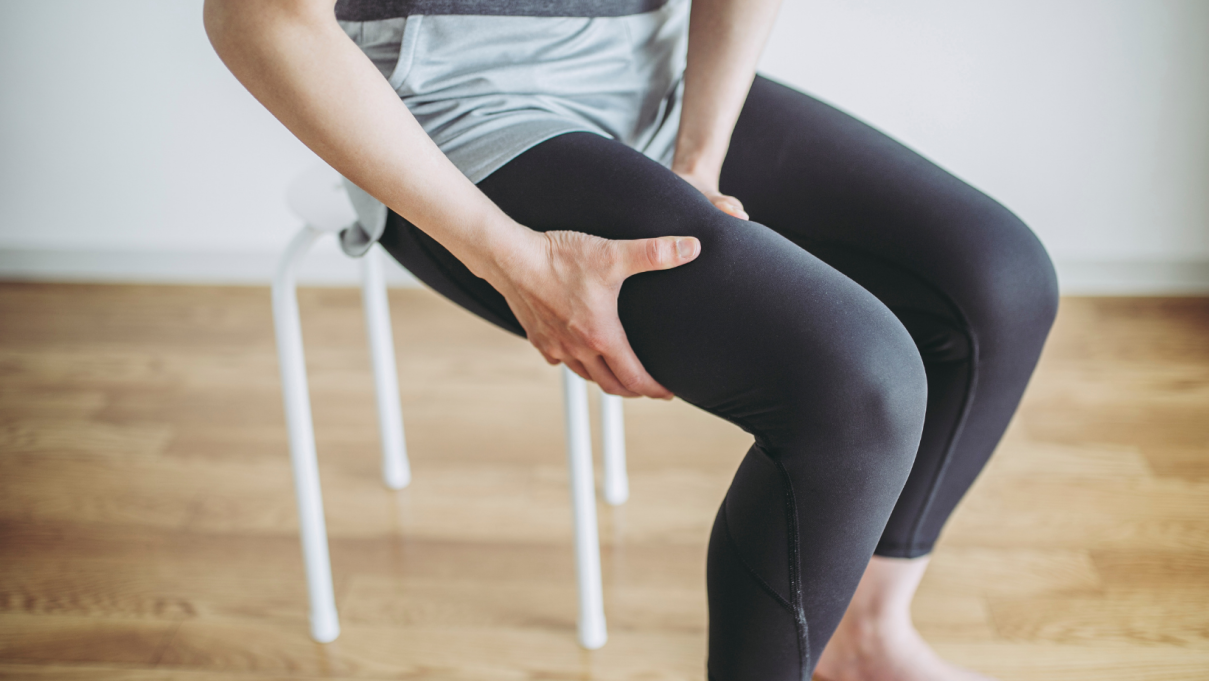 woman sitting on a stool holding her leg