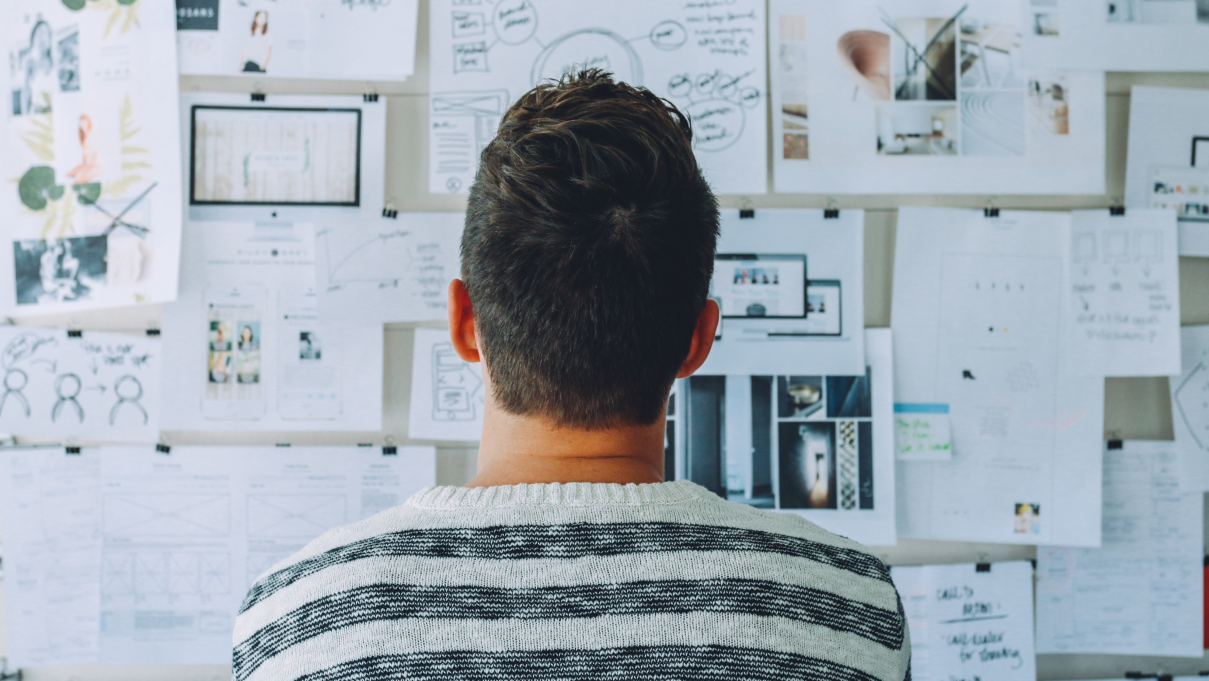 a person sitting facing away from the camera looking at a vision board