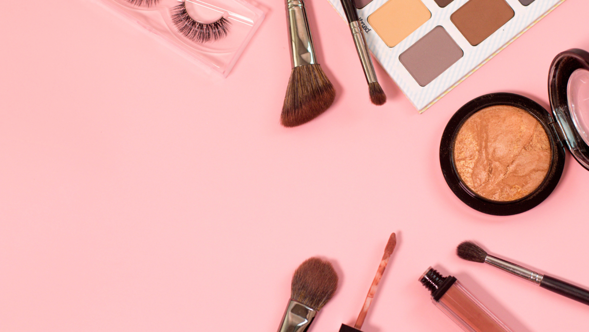 Makeup products spread out on a pink background